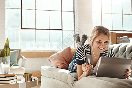 平板电脑 电子商务和女孩在沙发上用信用卡支付卡上的银行详细信息 在家沙发上放松的女人 带着快乐和满意的微笑进行网上购物交易图片