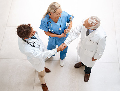 一个医生团队在医院握手的高角度镜头 拍到了一队人手摇晃的医生男性成人工作工人黑发护士女性团体耀斑微笑图片