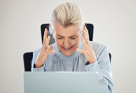 一位成熟的女商务人士在办公室用笔记本电脑工作时 心力很紧 非常紧张图片