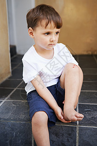 跌跌撞撞是童年的一部分 一个膝盖上有伤口的小男孩坐在楼梯上图片