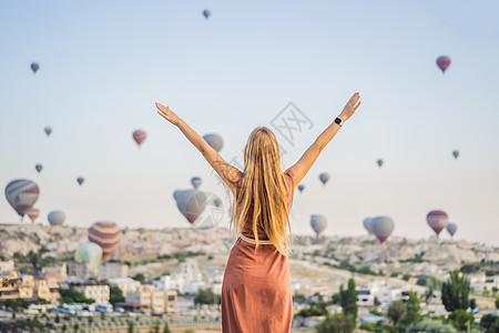 土耳其气球在土耳其卡帕多细亚看热气球的女游客 土耳其概念中的快乐旅行 山顶上的女人享受美妙的景色蜜月日出冒险女孩岩石吸引力自由天空旅游气球背景