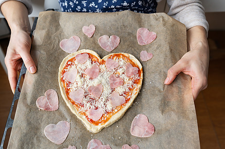 一个拿着披萨盘的厨师 用火腿装饰成心脏 情人节的惊喜概念 她喜欢吃人肉和做人肉图片