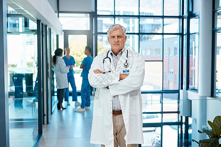 我们把您的健康放在首位 一位成熟的男医生双臂交叉站在一家现代医院图片