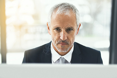 紧跟最新的商业趋势 一个专注的成熟商务人士在办公室里用他的电脑工作图片