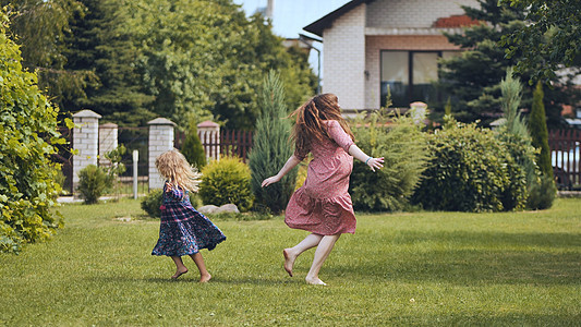 一个母亲和她的女儿在房子外的花园里转动图片
