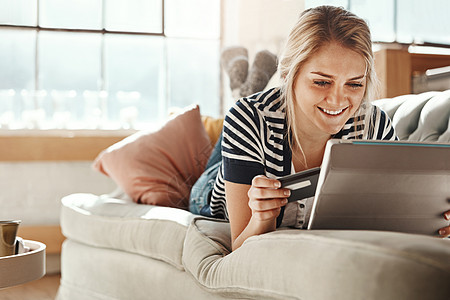 平板电脑 在线购物和在客厅沙发上对信用卡在线支付感到满意的女孩 放松的女人在家里的沙发上用满意的微笑检查卡的详细信息以进行电子商图片