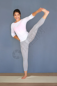 伸展使你变得更加灵活 一个运动的年轻女子在灰色背景下做瑜伽 拍了整整一张照片图片