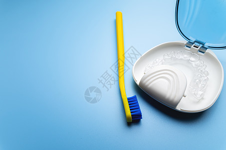 蓝色背景上的特制储物盒中装有牙刷的透明牙套 特写日常牙科护理概念背景图片