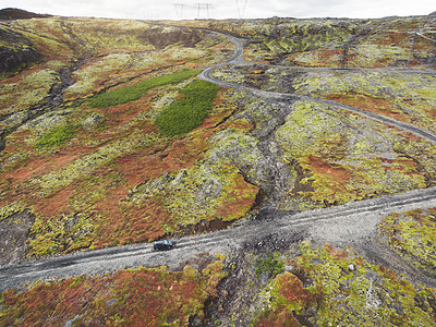 汽车在冰岛高地上开着车 在秋天的沙砾路上图片