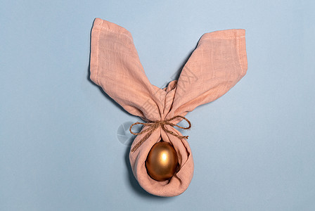 复活节兔子蛋 作为兔子的金蛋装饰 兔子耳朵 复活节快乐的概念 柔和的蓝色背景图片