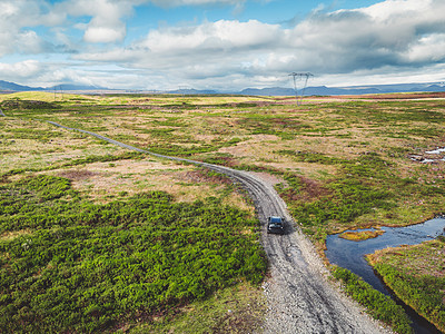 车开在冰岛内陆一条路经冰岛的砂砾路上 周围环绕着充满活力的绿色山丘图片