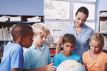 老师与学生掌握地理知识 一位漂亮的年轻地理老师使用地球仪教她的学生了解世界背景