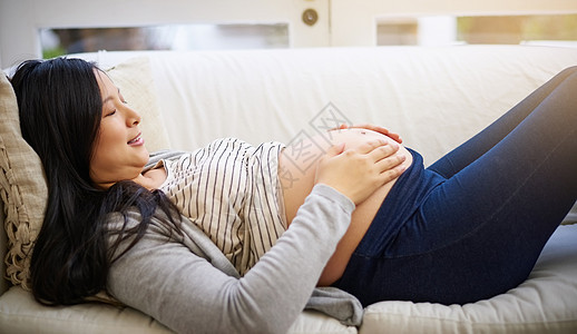 一位迷人的年轻孕妇在家沙发上放松 在沙发上舒舒服服地休息图片