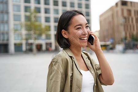 现代年轻的亚洲女孩在手机上交谈 在城市街道上使用电话 女人微笑着用智能手机打电话给某人学生快乐女性出租车城市细胞技术黑发街道互联图片