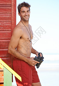 他在海边留意危险 海滩上一位英俊的年轻救生员衣服微笑肚子黑发调子成人幸福身体男人手表图片