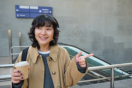 在耳机 听音乐 享受喝咖啡 站在街上 火车站等地的黑发女人互联网游客车站快乐咖啡旅游街道女士城市女孩图片