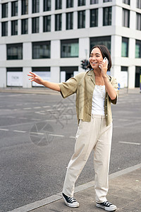 年轻女性向出租车司机挥手 打电话或用手机交谈 叫车 露街户口的青年妇女图片