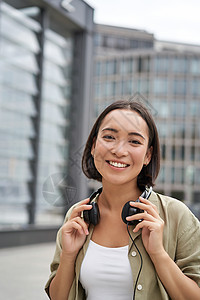 人们 微笑着的亚洲女孩 带着耳机 在市中心的街上跳舞 看着开心的样子快乐手机青少年技术商业互联网音乐青年电话女性图片