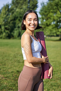 带着橡胶垫微笑的健身女孩 站在公园里穿着制服参加锻炼和体育活动 在草坪上做户外瑜伽女孩快乐福利赛跑者女士工作跑步训练运动装运动图片