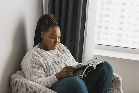 留辫子的非洲裔美国女性在家阅读杂志  休闲和生活方式概念读者八卦情感生活卧室报纸微笑文学享受快乐图片