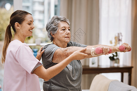 妇女 老年人或理疗师在健康诊所 医疗中心或疗养院客厅帮助哑铃 微笑 快乐或物理治疗师护士和老年患者体重康复重量病人员工身体房间训图片