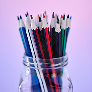 用于学校着色文具缩放的创意 艺术和绘图铅笔容器 用于创意教育的紫色渐变工作室背景中带有彩色铅笔的玻璃罐的特写图片