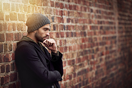 一个英俊的年轻男子 穿着时髦的冬天服饰 站在砖墙上图片