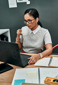 一位年轻女商务人士在办公室用笔记本电脑工作时喝咖啡 在办公室里喝酒 我正想着如何做呢图片