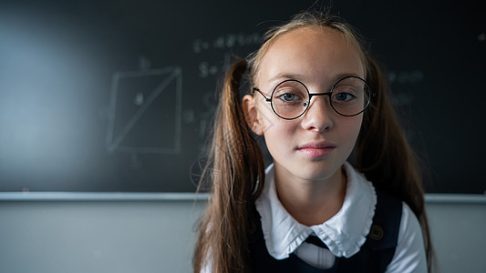 教室里一个戴眼镜的天主教女孩的肖像 女学生在黑板上回答知识科学答案学生孩子学习粉笔教育木板大学图片