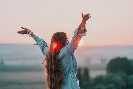 夏天 快乐的女人背对着夕阳站在大自然中 张开双手 浪漫美丽的新娘穿着白色波西米亚风连衣裙在日落时与群山合影裙子假期幸福海滩婚礼奢图片