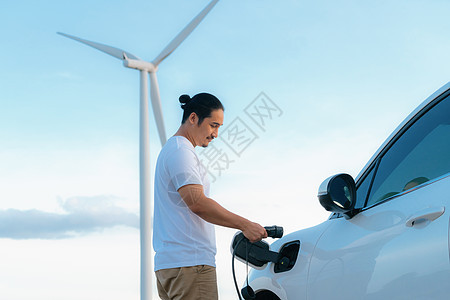 进步的人 他的EV汽车和风力涡轮机 是可再生能源的概念电池汽车涡轮男人地平线场地可持续充电器绿色电动车图片
