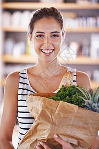 开始我的新饮食 一个有吸引力的女人 在厨房里拿着一袋杂货图片