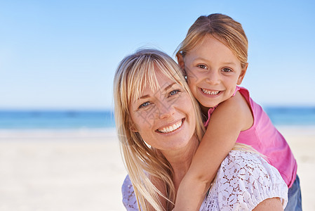 坐在海滩上的母亲和女儿的肖像 她与生俱来地坐在沙滩上图片