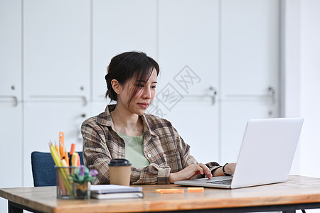 在创造性工作场所使用计算机笔记本电脑的女设计师图片