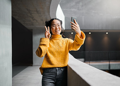 女人 在办公楼里和平自拍 在互联网上微笑和快乐 摆姿势和表情符号 亚洲 女孩和企业家 使用智能手机拍照 和平标志和手拍照图片