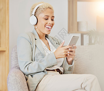 女商务人士 耳机和电话在办公室使用技术播放音乐或视频 黑人女性在沙发上在社交网络 音乐或网络应用程序上微笑 听有趣的播客图片
