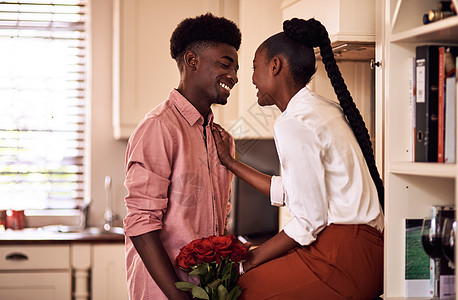 我知道玫瑰是你的最爱 一个深情的年轻人在家里的厨房里给妻子一束玫瑰花图片