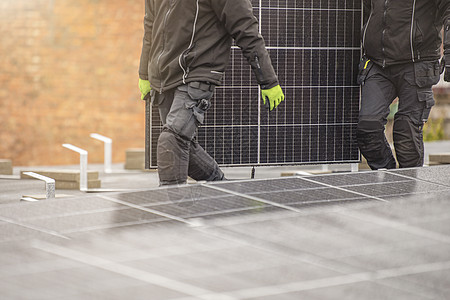 安装太阳能电池板的过程 太阳能电池板安装人员在屋顶工作 安装人员携带太阳能电池板模块到安装现场 绿色和可再生能源概念车站商业工程图片