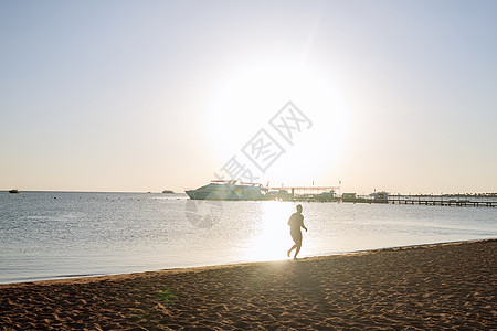 一个人在黎明时分沿着海滨奔跑的轮廓 健康的生活方式 在海滩上健身锻炼图片