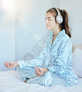 卧室里的瑜伽 冥想或禅宗女性戴着耳机播放放松的收音机 平静的音乐或播客 莲花姿势的和平 心理健康或灵性女孩冥想正念或健康图片