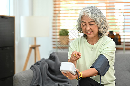 成熟的女人用数字眼压计检查血压和心率 老年保健和医疗理念图片