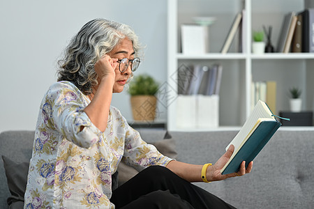 由于视力问题 试图看书的老妇人看书有困难图片