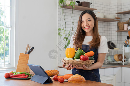 在厨房里做菜的女人准备材料 准备烹饪 看药片上的食谱沙拉电脑博客收据食物爱好互联网蔬菜笔记本厨师图片