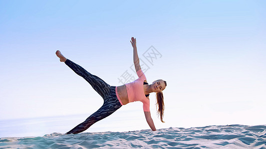 健康 年轻漂亮的女人在沙滩上 在日出时锻炼腹斜肌 锻炼平衡和协调 深肌张力图片