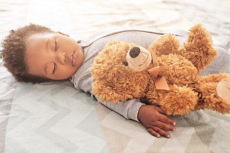 一个小男孩睡在床上 和一只泰迪熊睡在一起 她的床很甜 她叫艾丽克丝图片