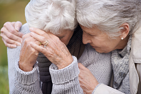我是来帮你擦眼泪的……一位年迈的老年妇女坐在户外安慰她的朋友图片