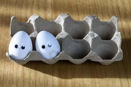 纸箱里白鸡蛋上的滑稽面孔 厨房桌子上放着有机鸡蛋 特写大动画眼睛 幽默 食物和复活节假期的概念情感农场季节微笑人群纸板假期盒子快图片
