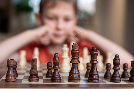 年轻的白人孩子在大棋盘上下棋 小学生面前桌上的棋盘思考下一步运动乐趣典当骑士专注国王思维竞赛童年优胜者图片