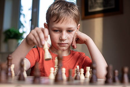 年轻的白人孩子在大棋盘上下棋 小学生面前桌上的棋盘思考下一步女王思维爱好学习战略国际竞赛男生教育典当图片