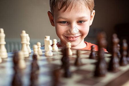 年轻的白人孩子在大棋盘上下棋 小学生面前桌上的棋盘思考下一步 锦标赛图片